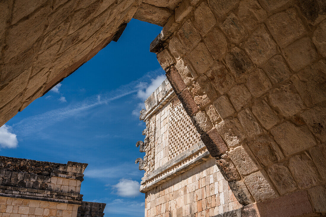 Der Blick durch einen Bogen im Viereck der Vögel in den Ruinen der Maya-Stadt Uxmal in Yucatan, Mexiko. Chaac-Masken schmücken die Ecke des Nonnenklosters. Die prähispanische Stadt Uxmal - ein UNESCO-Weltkulturerbe.