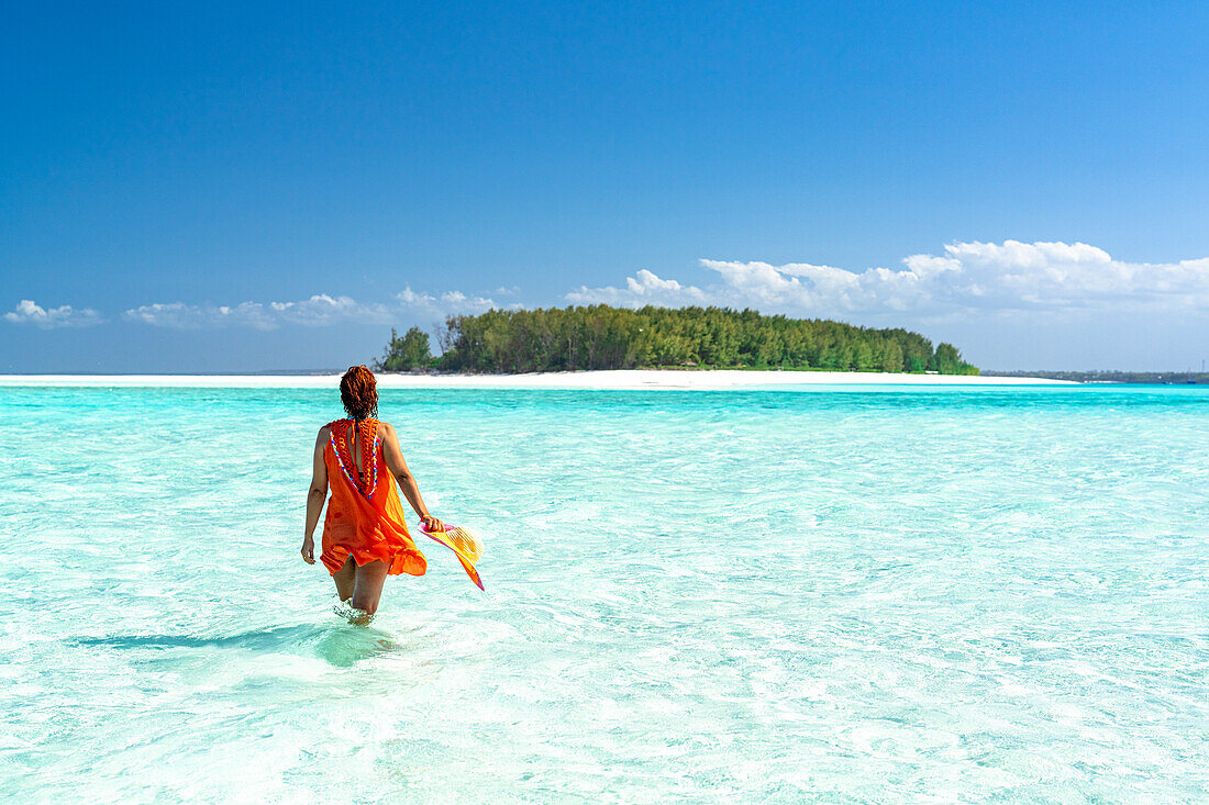 Woman admiring an exotic island standing in the crystal blue sea, Zanzibar, Tanzania, East Africa, Africa