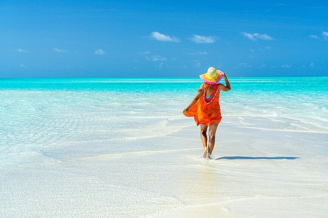 Woman with hat walking to the crystal clear sea, Zanzibar, Tanzania, East Africa, Africa