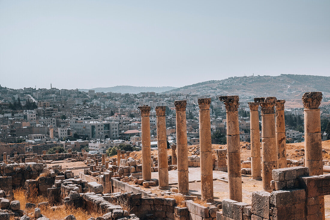 Die Ruinen eines römischen Tempels, mit der modernen Stadt Jerash im Hintergrund, Jerash, Jordanien, Naher Osten