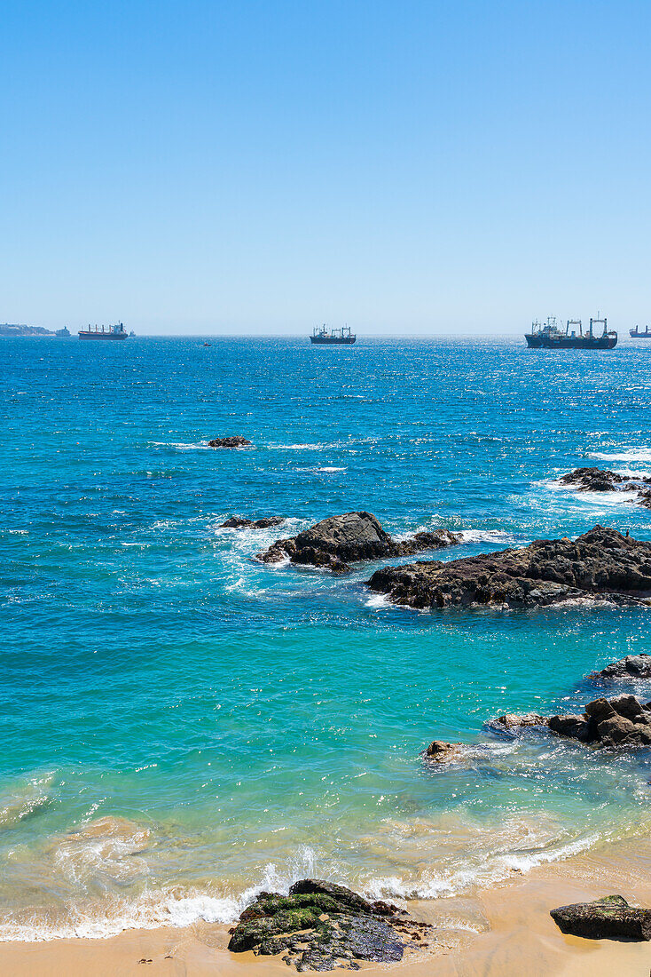 Rocky coastline and ships on sea, Caleta Abarca beach, Vina del Mar, Valparaiso Region, Chile, South America