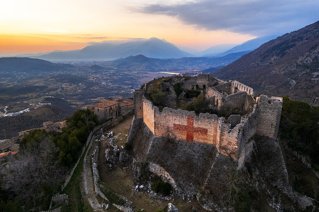 Luftaufnahme der mittelalterlichen Burg von Vicalvi mit Blick auf das Tal mit rotem Kreuz auf der Umfassungsmauer, bei Sonnenuntergang, Vicalvi, Provinz Frosinone, Ciociaria, Region Latium, Italien, Europa