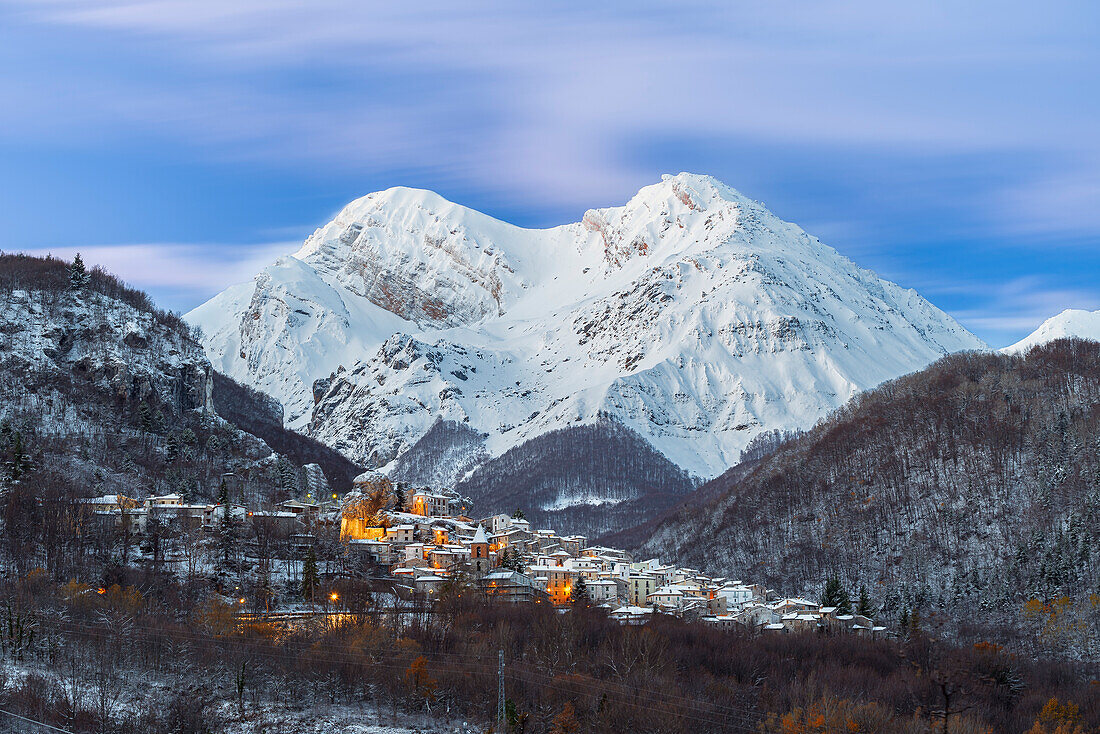 The small illuminated village of Pietracamela covered with snow and surrounded by Intermesoli snowy peak at dusk, Gran Sasso and Monti della Laga National Park, Apennines, Teramo district, Abruzzo region, Italy, Europe
