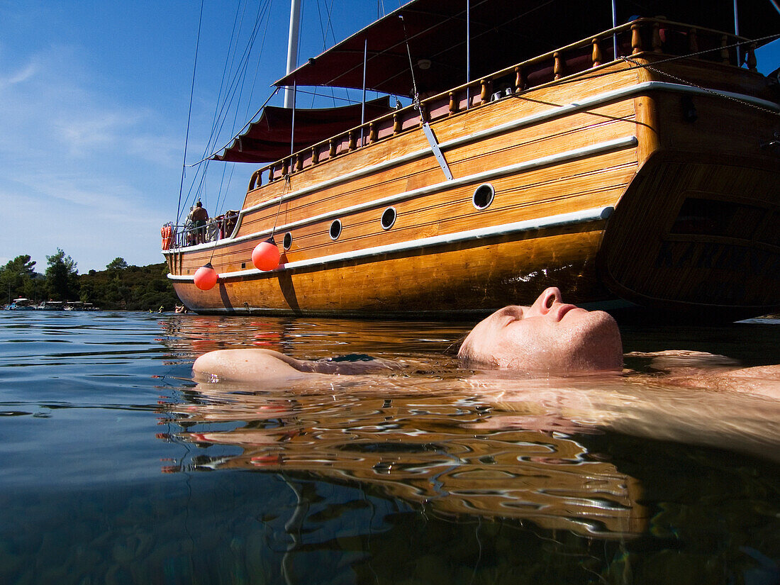 Male Swimmer Floating Alongside A Moored Boat