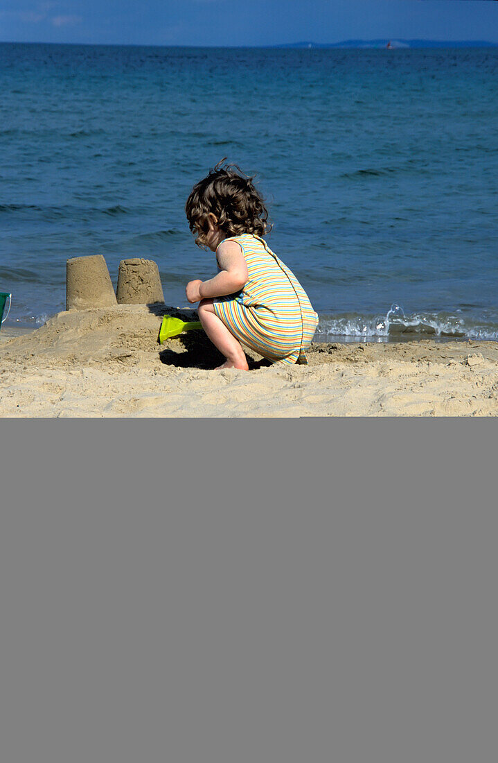 Girl Playing On The Beach Making Sandcastles