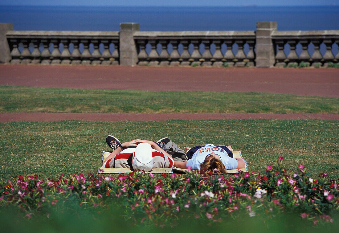 Couple Lying Down In Park By Sea