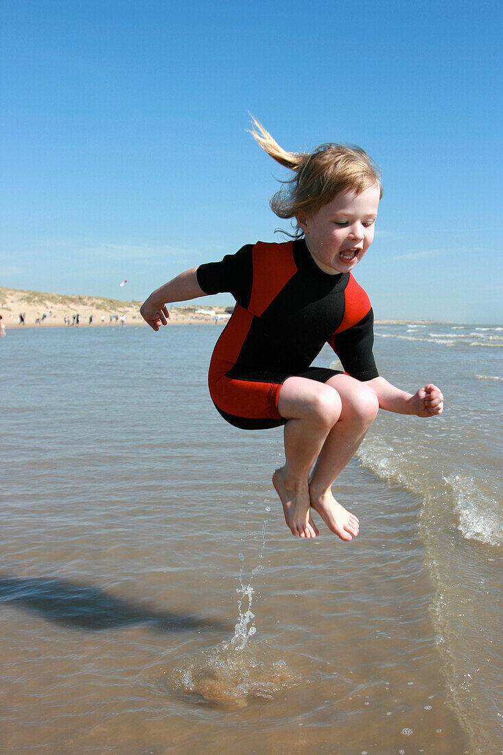 Young Girl In Wetsuit Jumping In Water