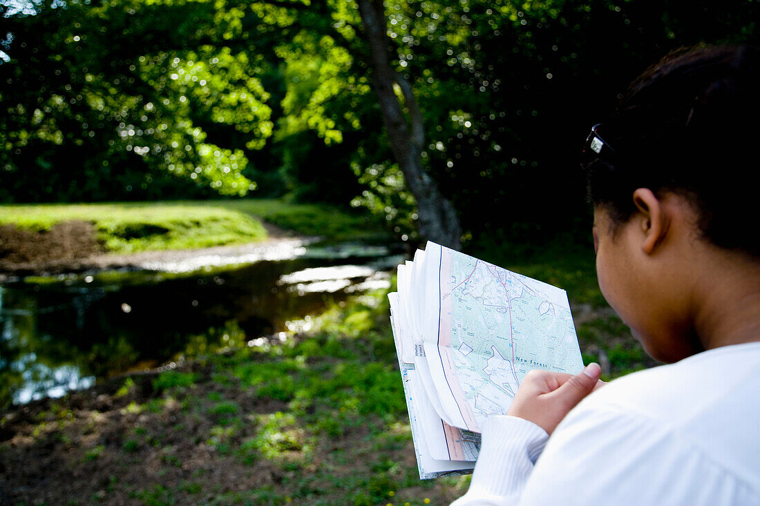 Frau schaut auf eine Karte im Wald