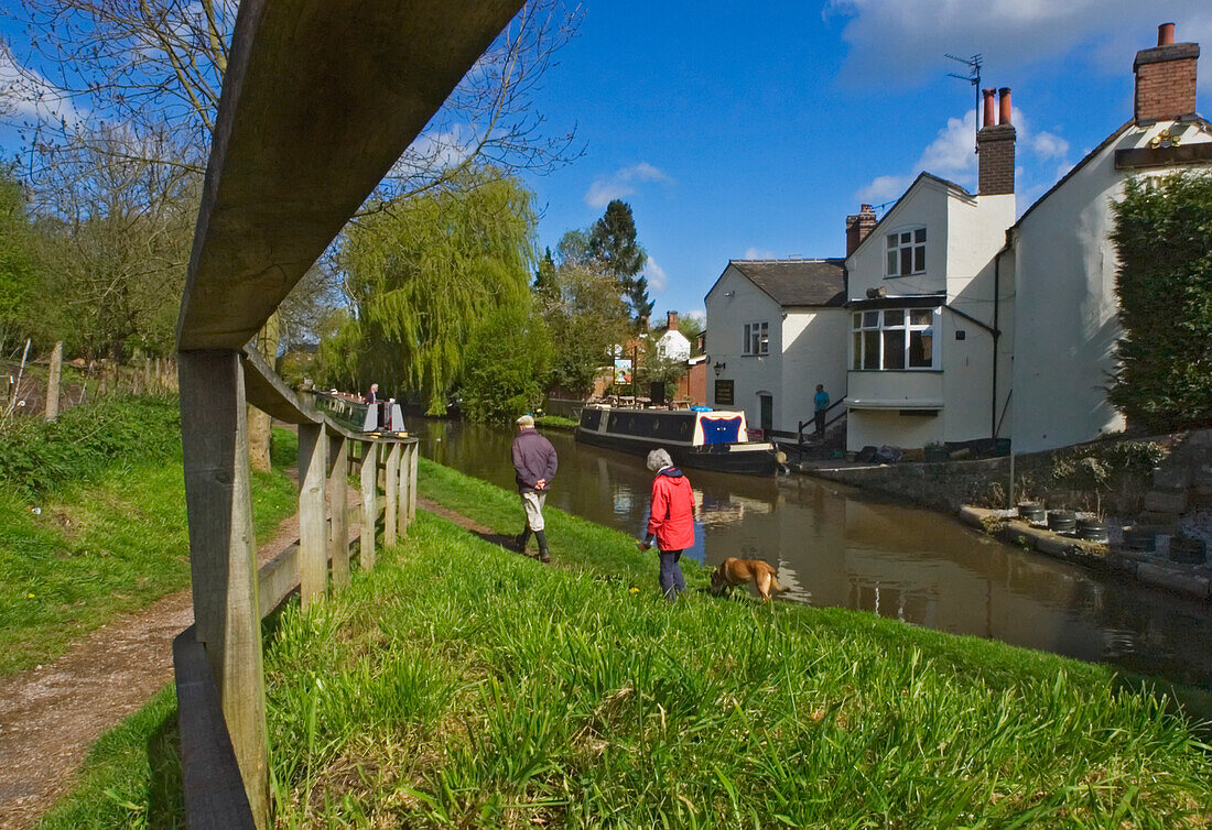 Paar geht mit seinem Hund am Flussufer des Shropshire Union Canal spazieren.