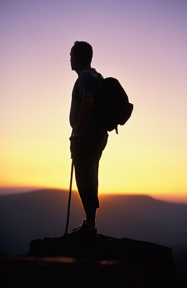 Silhouetted Man Standing On Mountain Peak