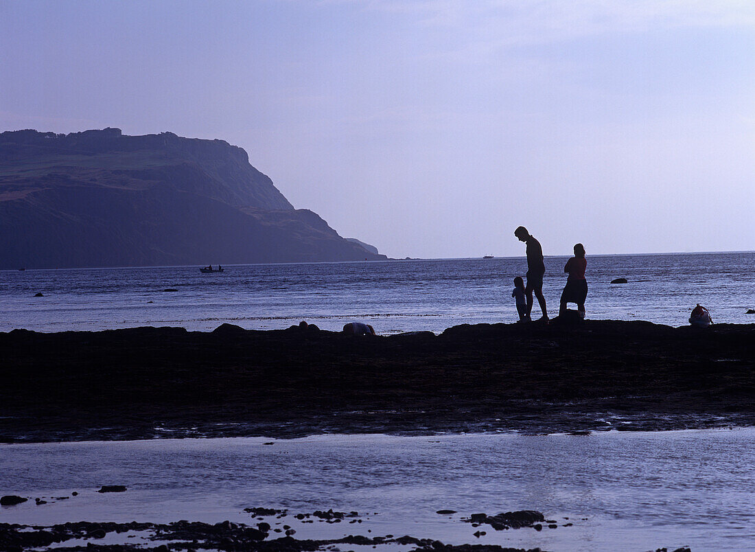 Family Walking Along The Seaside In Silhouette