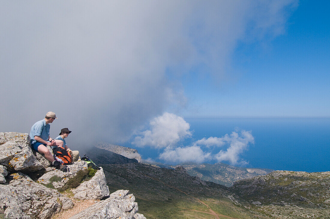 Two Hikers Sitting On Texi Mountain Peak, Looking At View, Side View