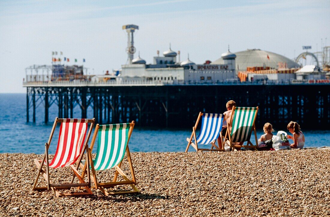Touristen mit Liegestühlen am Strand