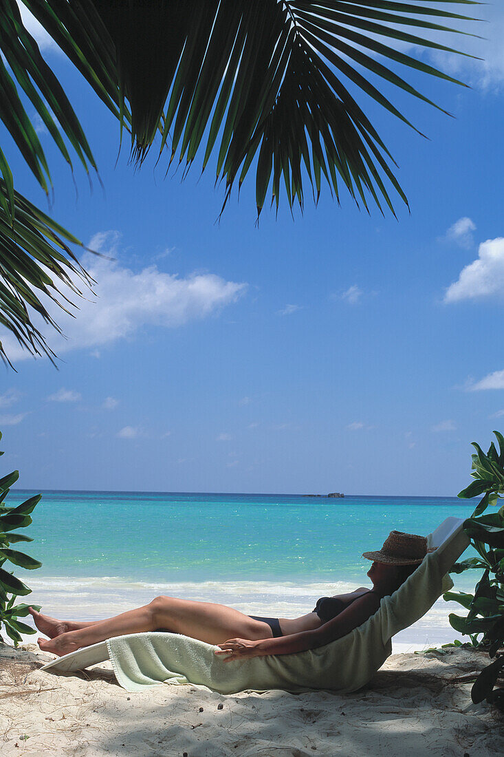 Seychellen, Praslin, Frau entspannt sich am Strand; Cote D'Or Beach