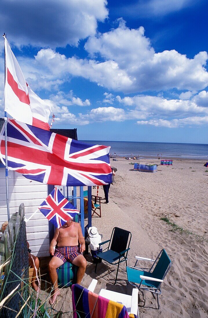 Familie vor einer Strandhütte mit britischen Flaggen