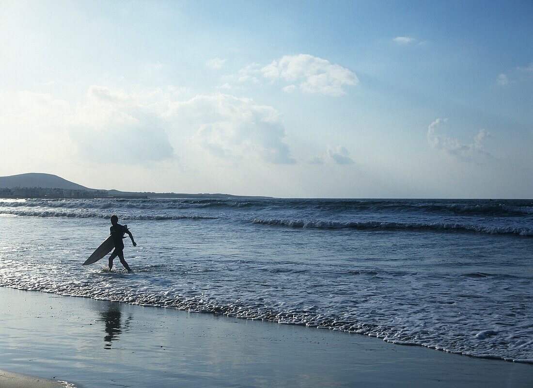Man With Surfboard Running On Beach