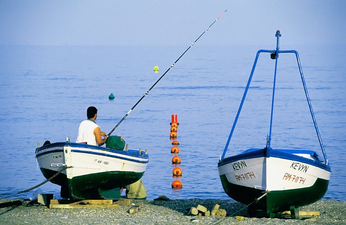 Man Fishing From Boat On Beach