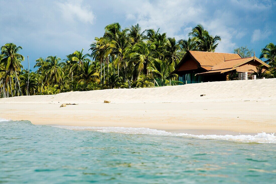 Haus zwischen Palmen am einsamen Strand
