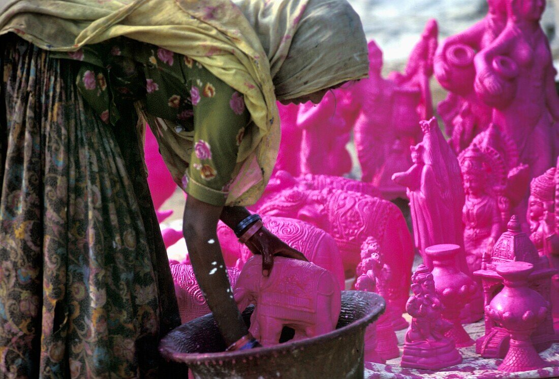 Rajasthanische Frau beim Färben von Tonstatuen vor dem Bemalen von Details