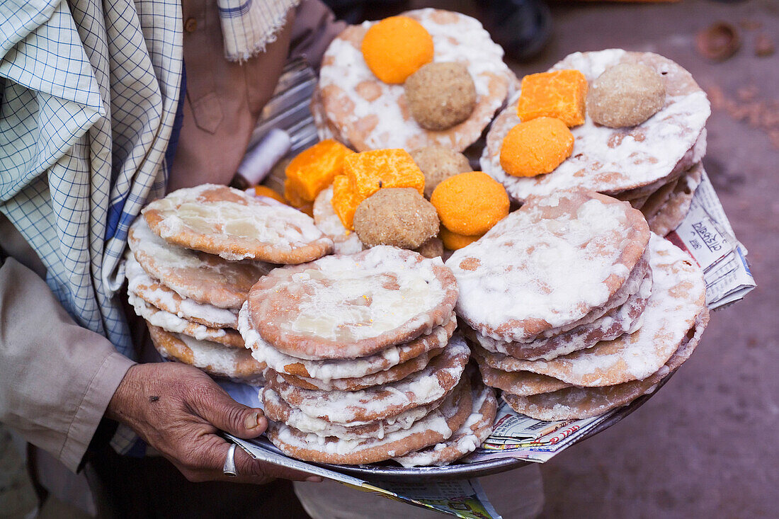 Person trägt Tablett mit gebackenen Opfergaben, Mittelteil, Nahaufnahme, Nadhwara, Rajasthan, Indien