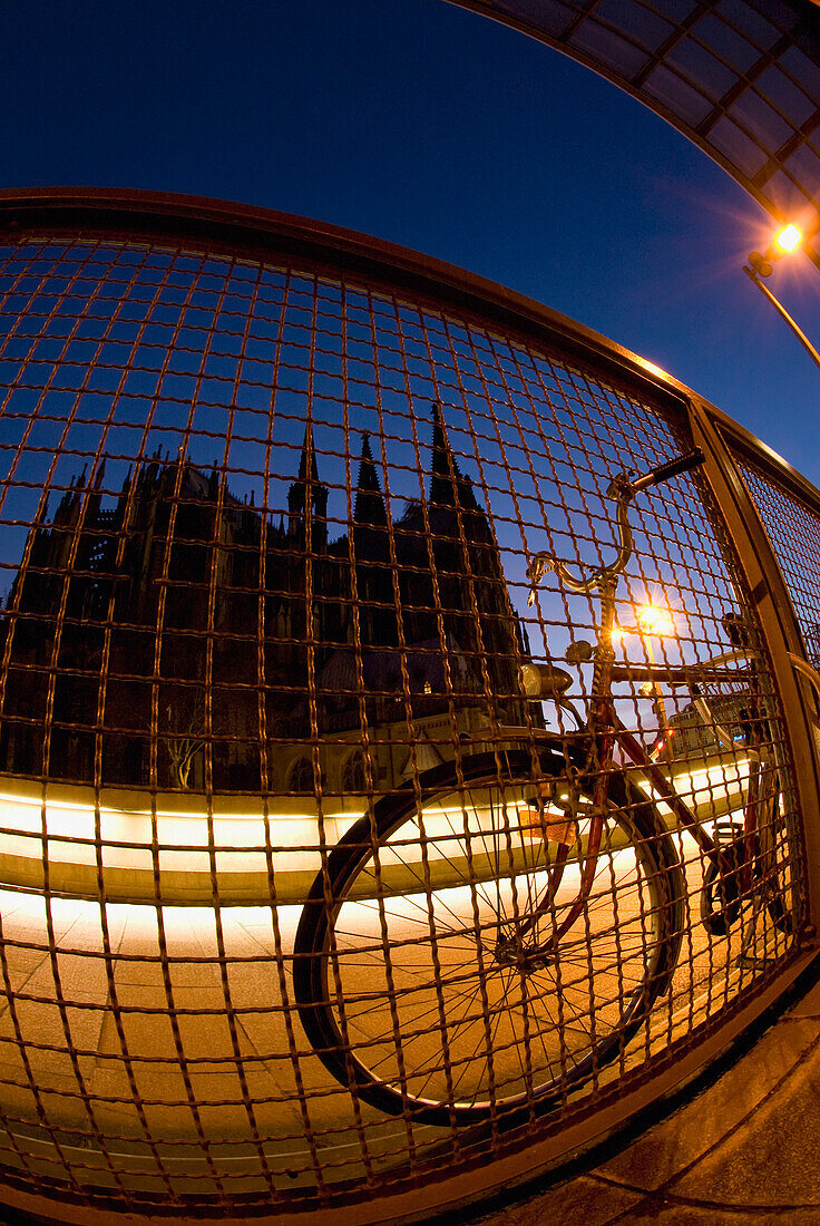 Fahrrad gegen Drahtzaun in der Abenddämmerung, Kölner Dom im Hintergrund, Köln, Deutschland