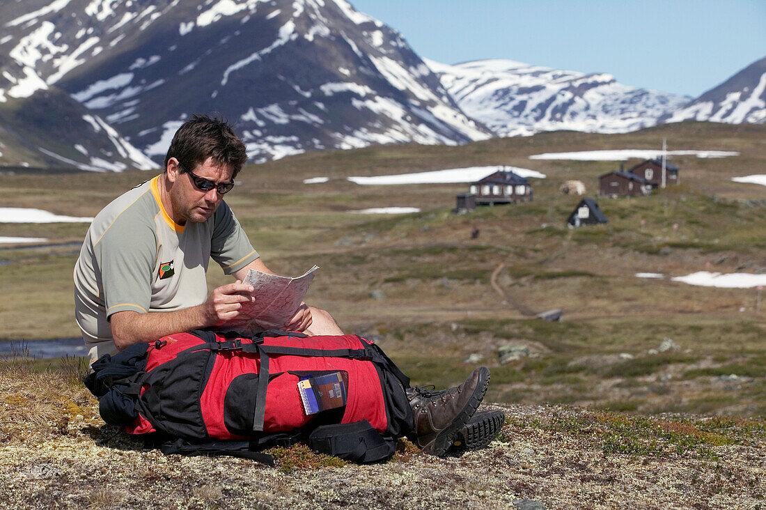 Wanderer, der im Tal sitzend die Karte prüft, Kungsleden Trail, Abisko, Schweden