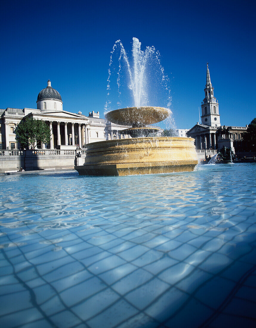 Springbrunnen am Trafalgar Square mit National Gallery und St Martins In The Fields Church, London.
