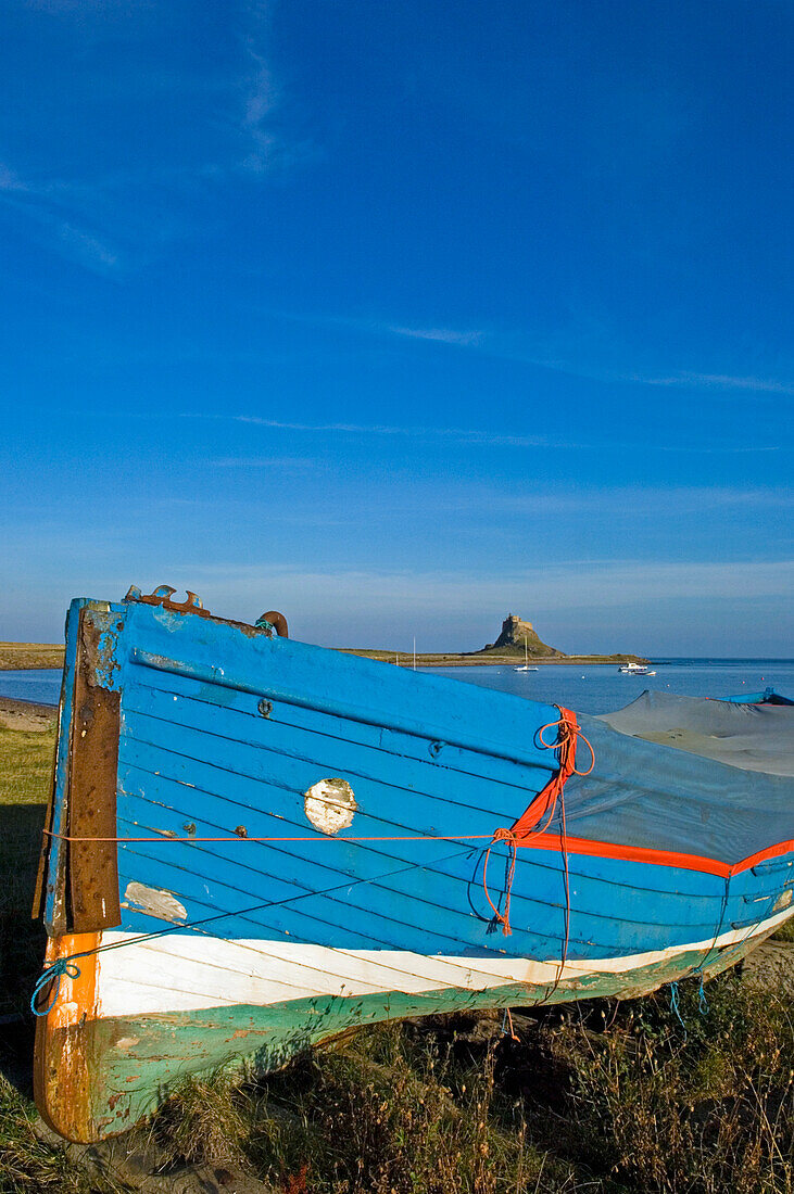 Boot am Ufer mit Lindesfarne Castle in der Ferne, Holy Island, Northumberland, Großbritannien