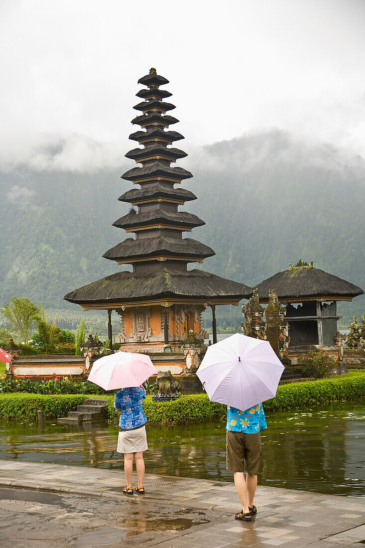 Tourists With Umbrellas At Temple