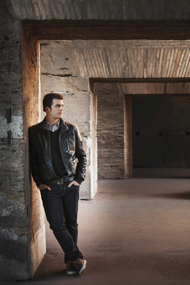 Portrait Of A Young Man Standing Against A Wall With Concrete Facade; Rome, Italy