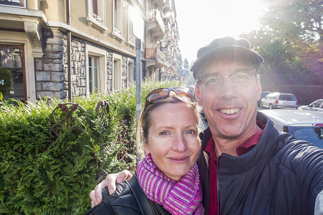 Ein Ehepaar nimmt ein Selbstporträt neben einer Straße und einem Gebäude auf; Lausanne, Schweiz