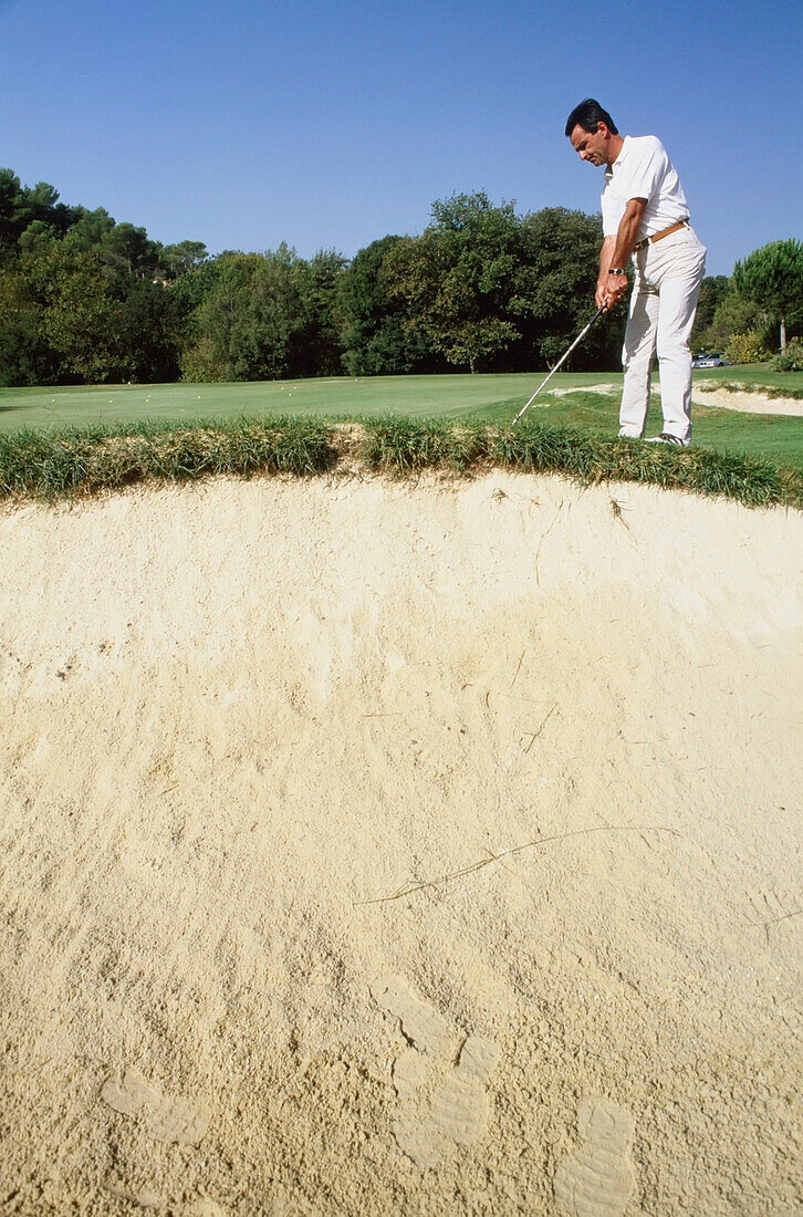 Mann spielt Golf in der Nähe der Sanddüne
