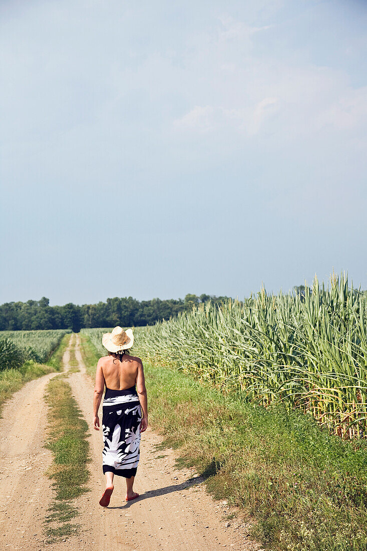 Frau auf Weg zwischen Maisfeldern
