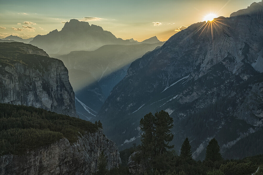 Die untergehende Sonne zeigt Sonnenstrahlen, die durch die Dolomitenberge im Nationalpark Tre Cime scheinen; Italien
