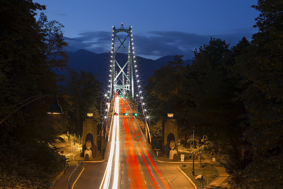 Langzeitbelichtung in der Dämmerung der Lions Gate Bridge mit Autoscheinwerfern, die über die Brücke streifen; Vancouver, British Columbia, Kanada