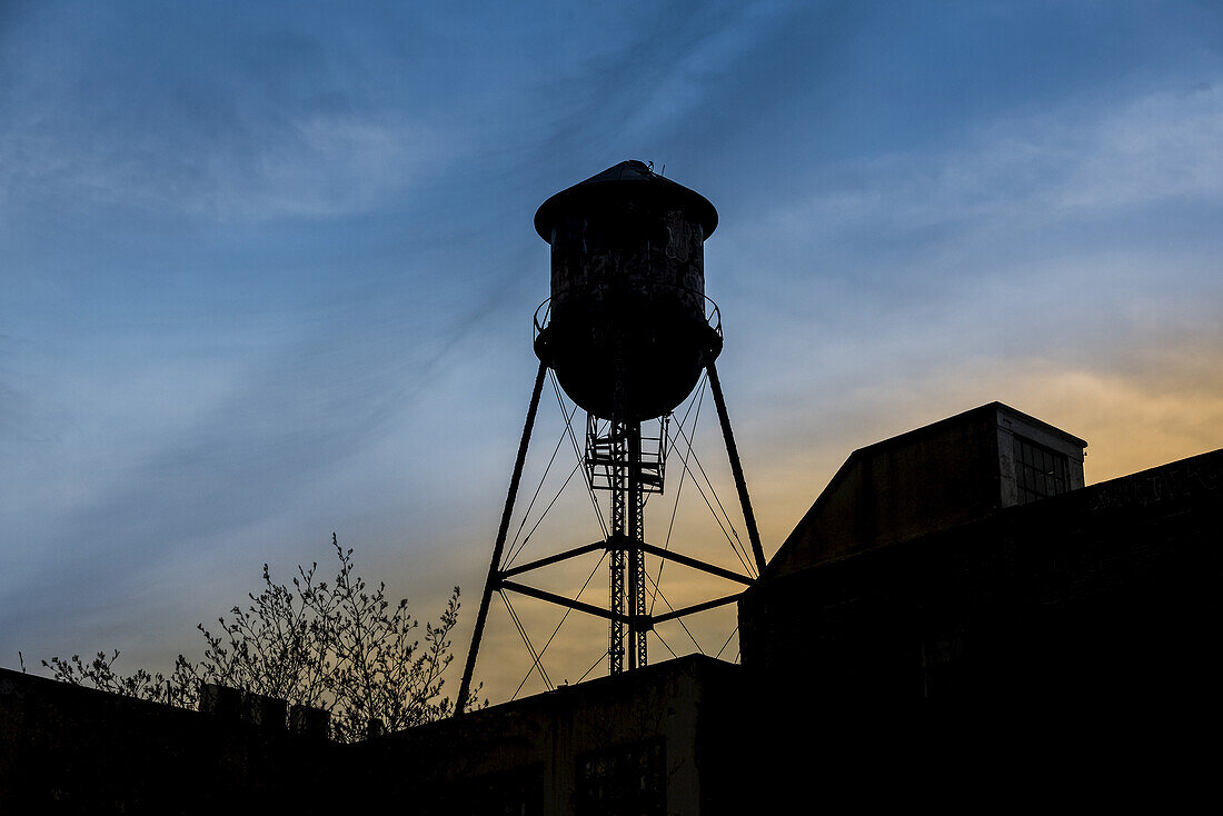 Silhouette of rooftops and water tank at sunset, Williamsburg; Brooklyn, New York, United States of America