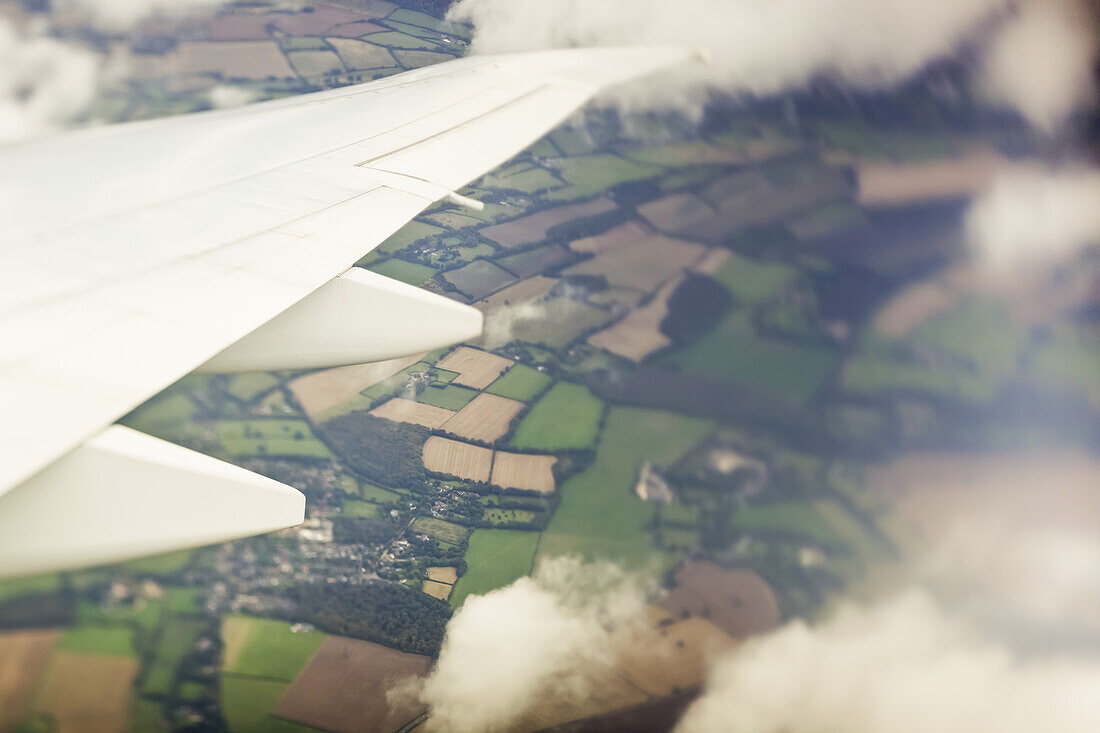 Aerial view of a patchwork landscape of farmland out the window of an airplane; Hastings, England