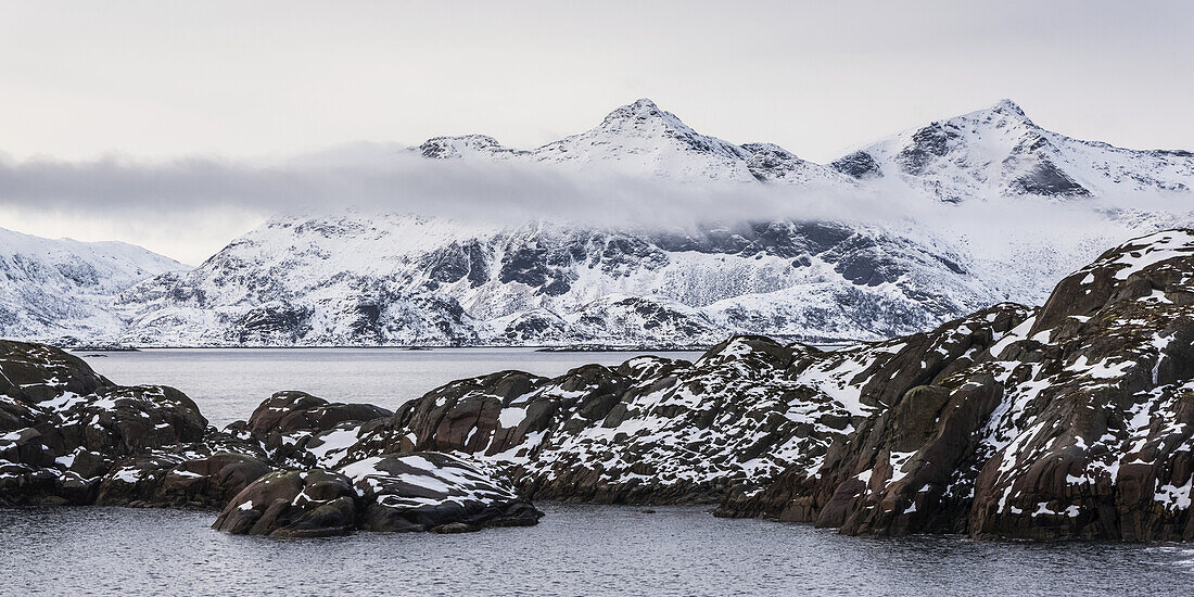 Snowy Landscape Of Rugged Mountains And Ocean Water; Nordland, Norway