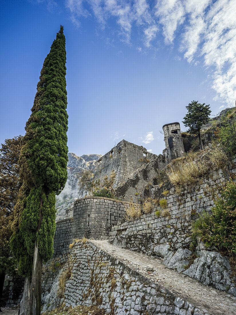 Stone walls and path of the Kotor Fortress with mountain and blue sky; Kotor, Montenegro