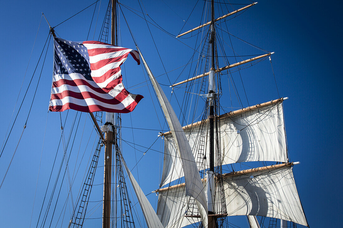 American flag hanging on a sailboat against a blue sky; San Diego, California, United States of America
