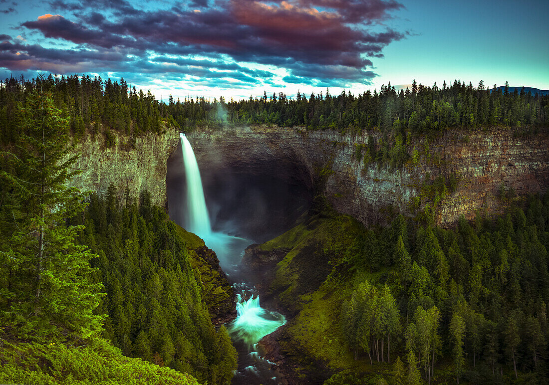 Illuminated waterfall flowing over a cliff in Wells Grey Provincial Park; Thompson-Nicola Regional District, British Columbia, Canada