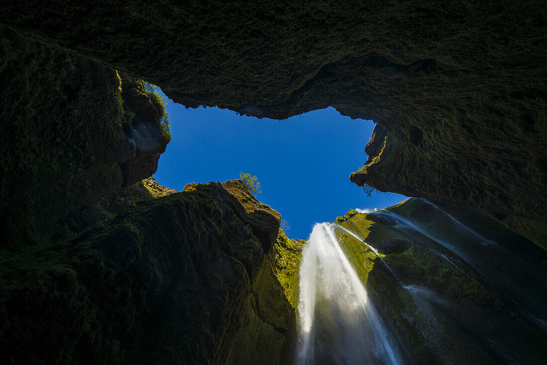 Blick auf einen kleinen Wasserfall in einem großen Loch nahe dem Seljalandsfoss; Island