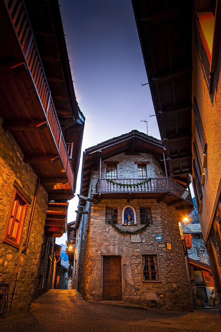 Alte Steingebäude und alte Kopfsteinpflasterstraßen beleuchtet in der Abenddämmerung, Dolonne, nahe Courmayeur, Aostatal, Italien