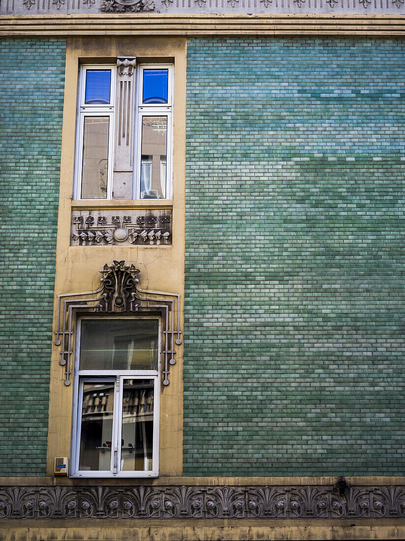 A building with green brick and windows with ornate decor; Belgrade, Vojvodina, Serbiade