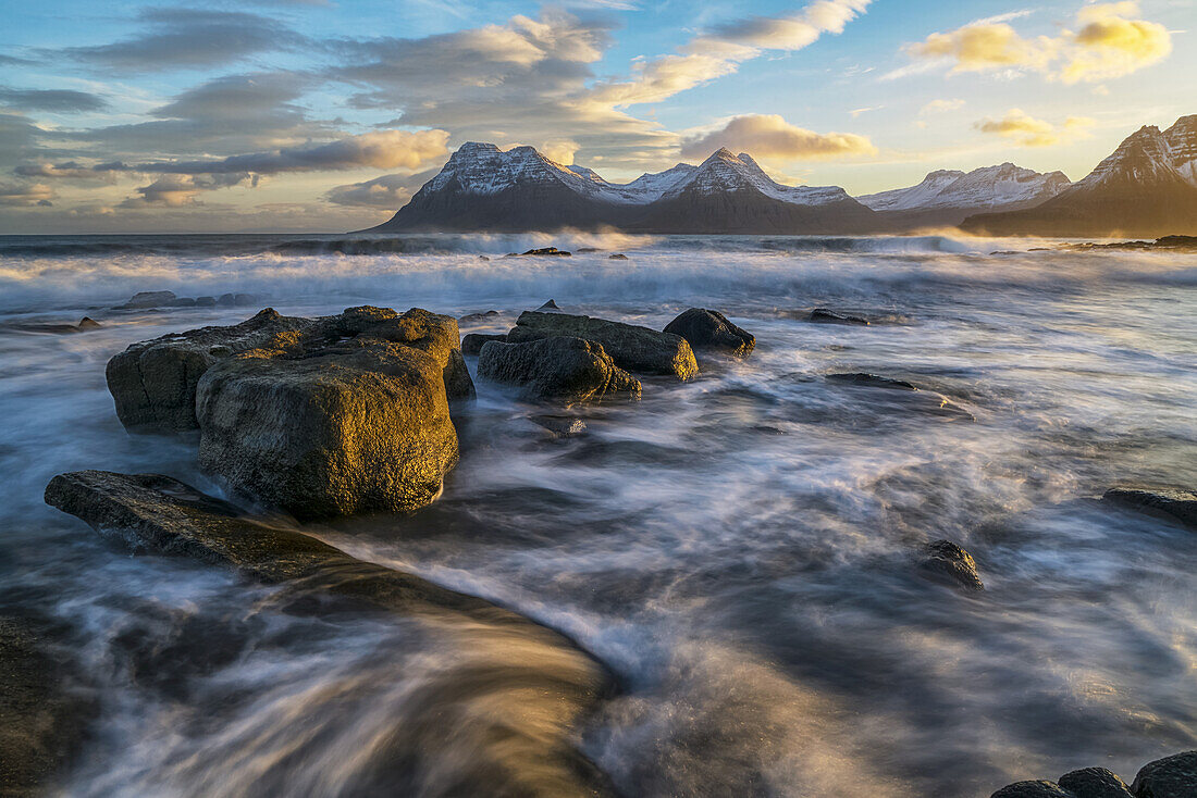 Sunset over the mountains of the Strandir Coast, Iceland as the surf pounds the shoreline; West Fjords, Iceland