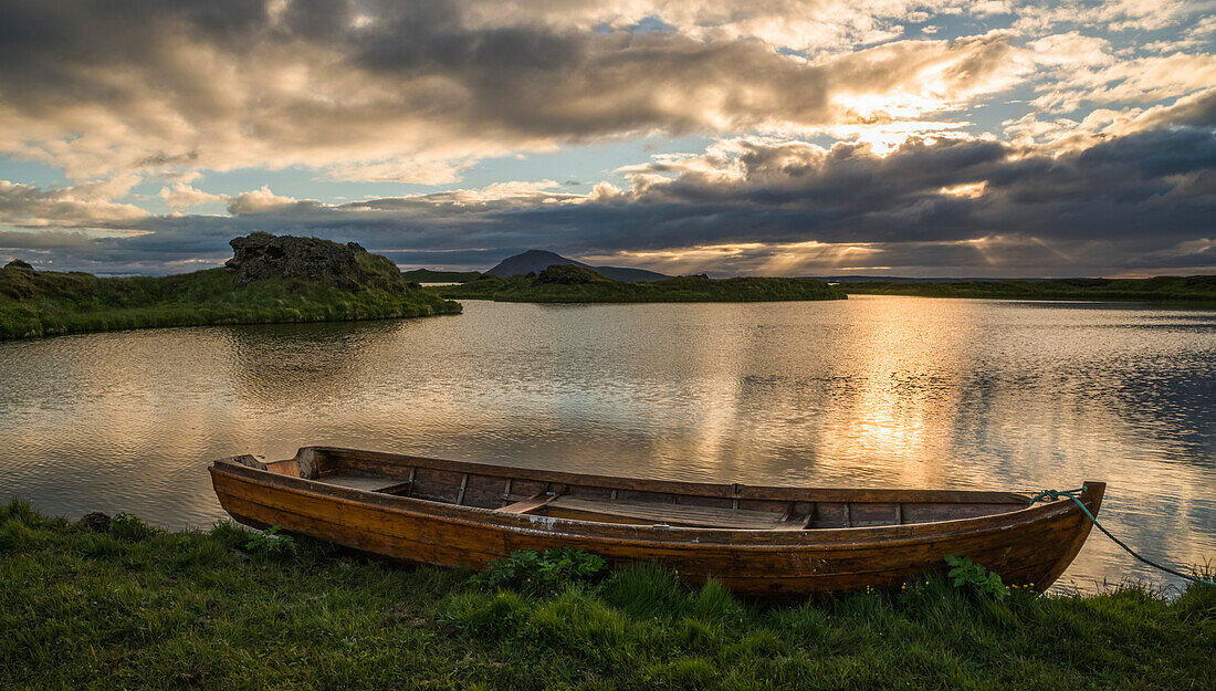 A boat lies in a placid Lake Myvatn, North Iceland at sunset; Iceland