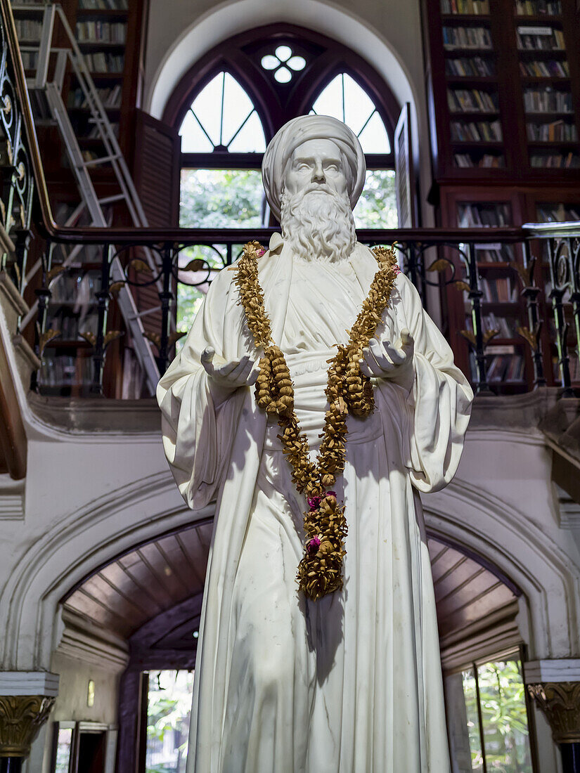 Weiße Statue einer männlichen Figur mit um den Hals drapierter Girlande und nach oben gehobenen Händen; Mumbai, Maharashtra, Indien.