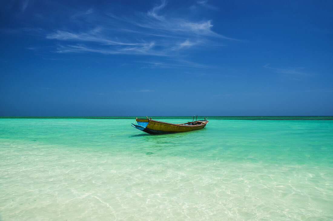 Ein Boot sitzt im seichten türkisfarbenen Wasser in einem tropischen Paradies; Andamanen, Indien.