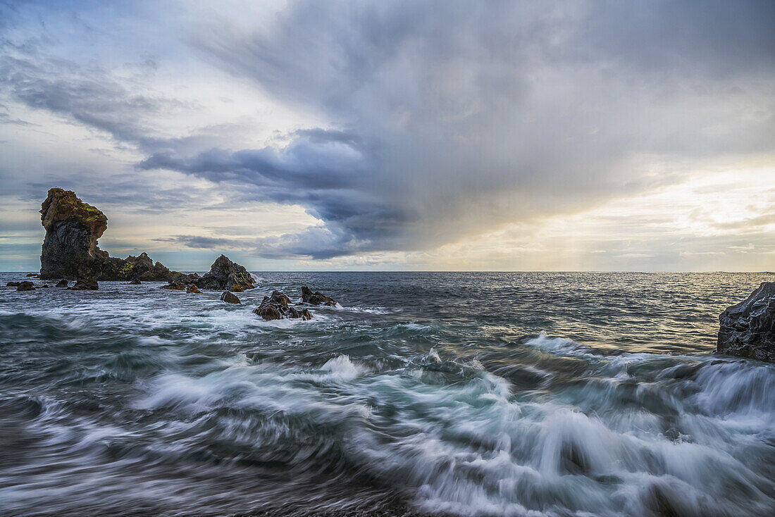 Waves crash against the shoreline of Djupalonssandur beach at sunset, Snaefellsness Peninsula; Iceland