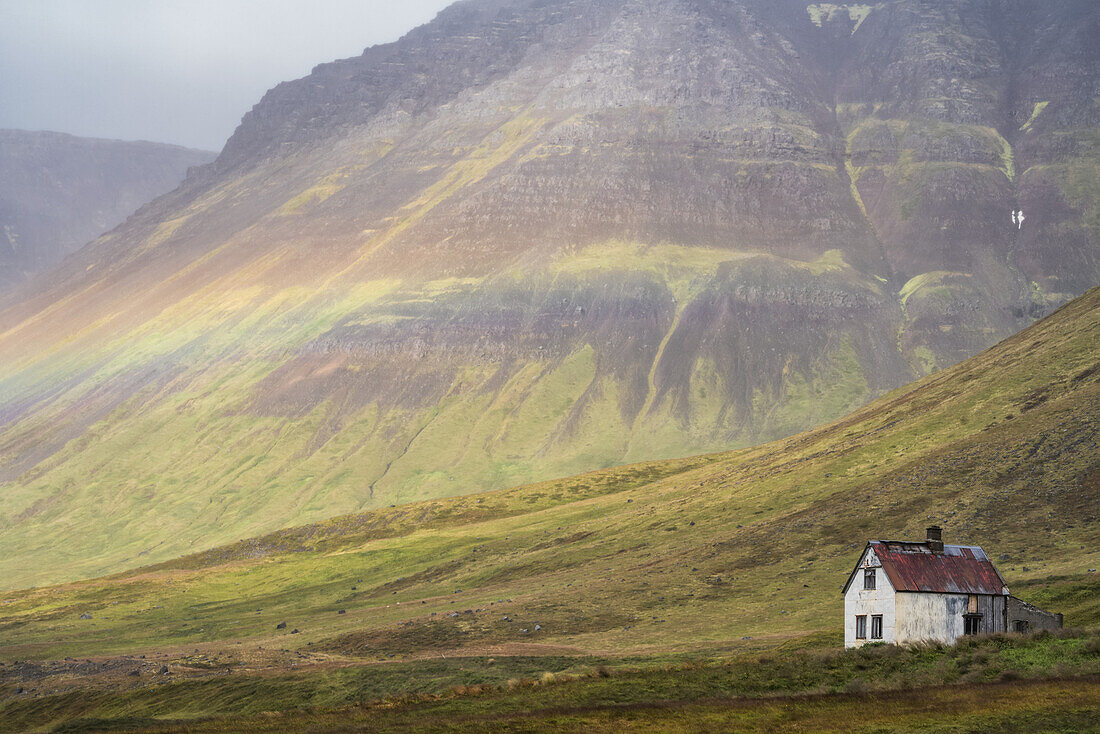 Schwacher Regenbogen über einem verlassenen isländischen Gehöft; Westfjorde, Island